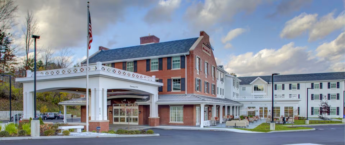 Exterior photo of a Hampton Inn hotel in Manchester Vermont with cotton wool clouds in the sky
