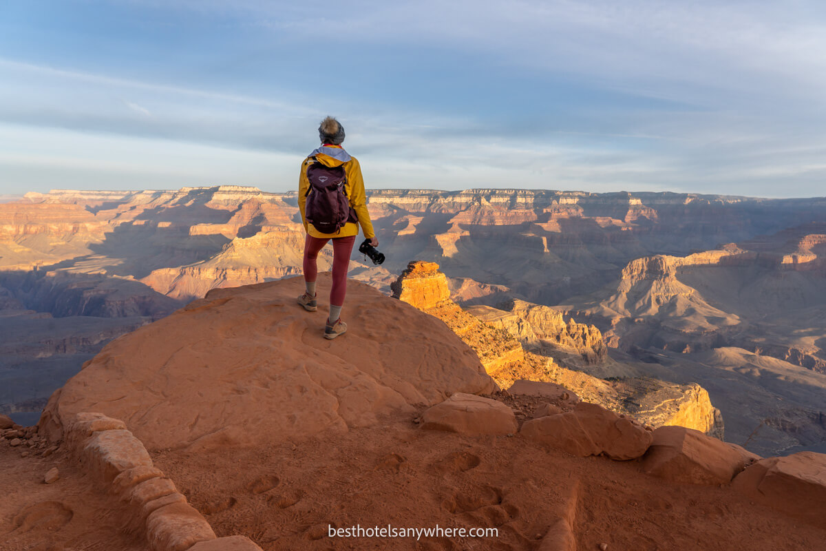 Hiker stood with camera in hand looking out over Grand Canyon in Arizona at sunrise