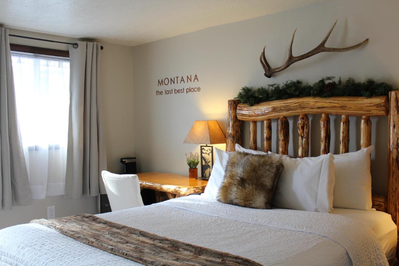 Inside a guest bedroom with bed backed by wooden frame and antlers on the wall