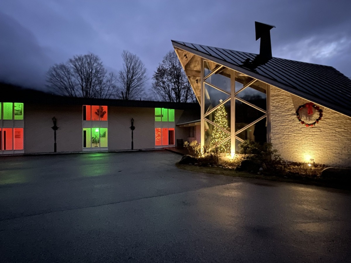 Exterior photo of a hotel in Manchester VT at night with green and red lights in windows