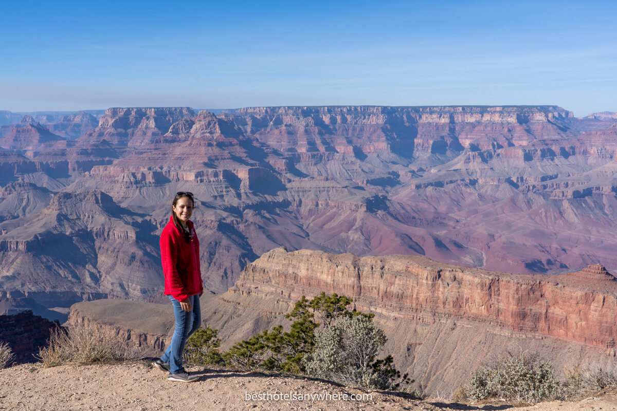 Tourist in jeans and red top standing on the edge of a gigantic canyon on a sunny but cool day