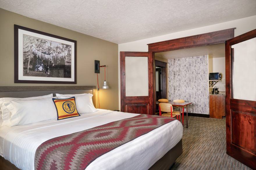 Upscale hotel room with large bed leading through doors to a table and chairs
