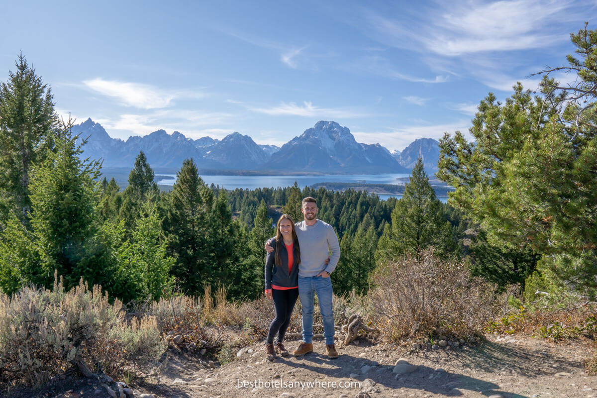 Couple hugging at a viewpoint overlooking mountains and a lake in Grand Teton near Jackson Wyoming