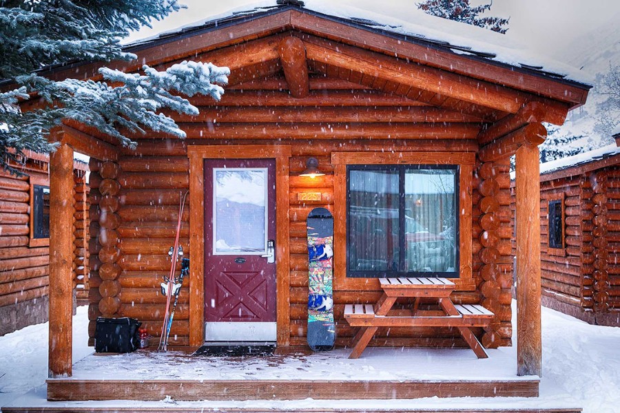 Exterior photo of a wooden log cabin in the snow