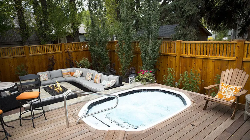 Outdoor jacuzzi and seating area around fire pit built into wooden deck
