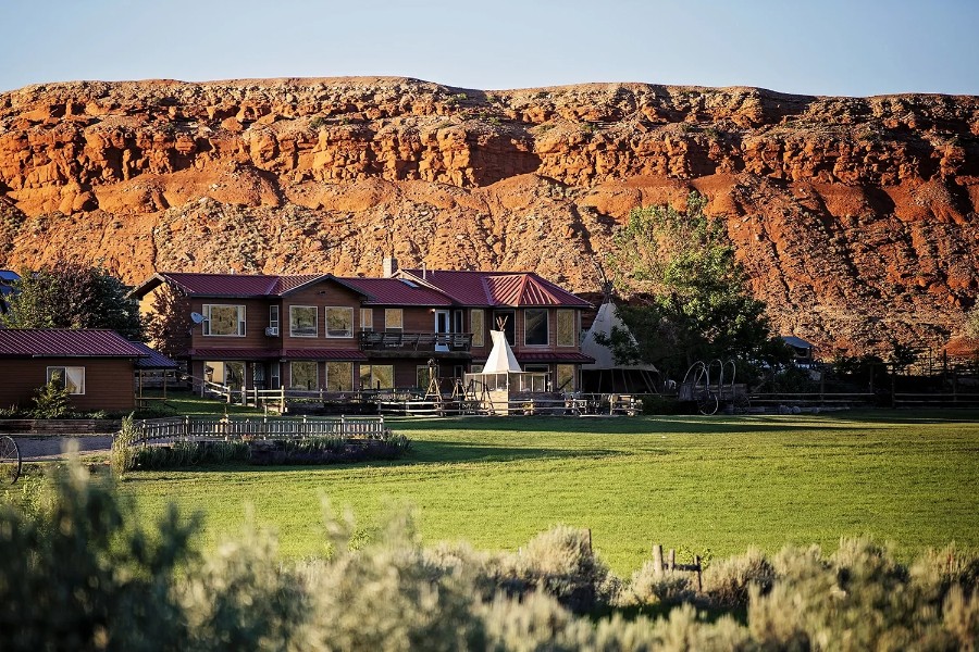 Exterior photo of a ranch in Cody WY with towering cliffs behind