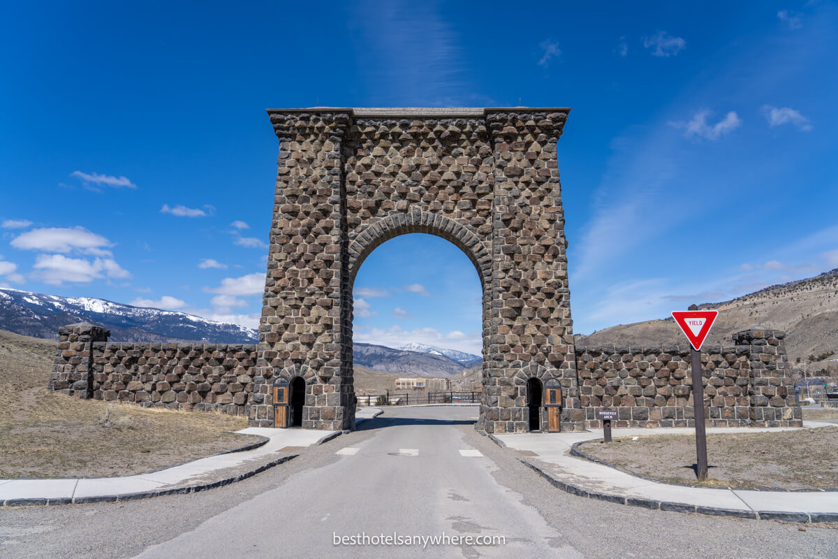 Looking at the Roosevelt Arch in Gardiner Montana with mountain views through the arch on a clear day