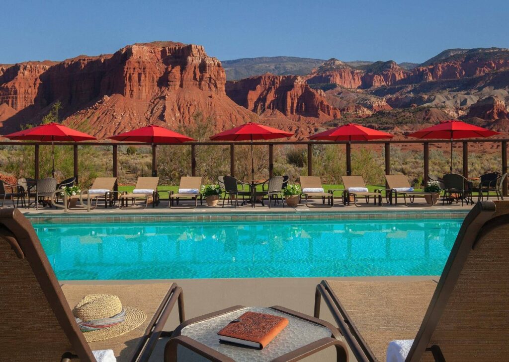 Sunloungers with a turquoise swimming pool and distant red rock mountains