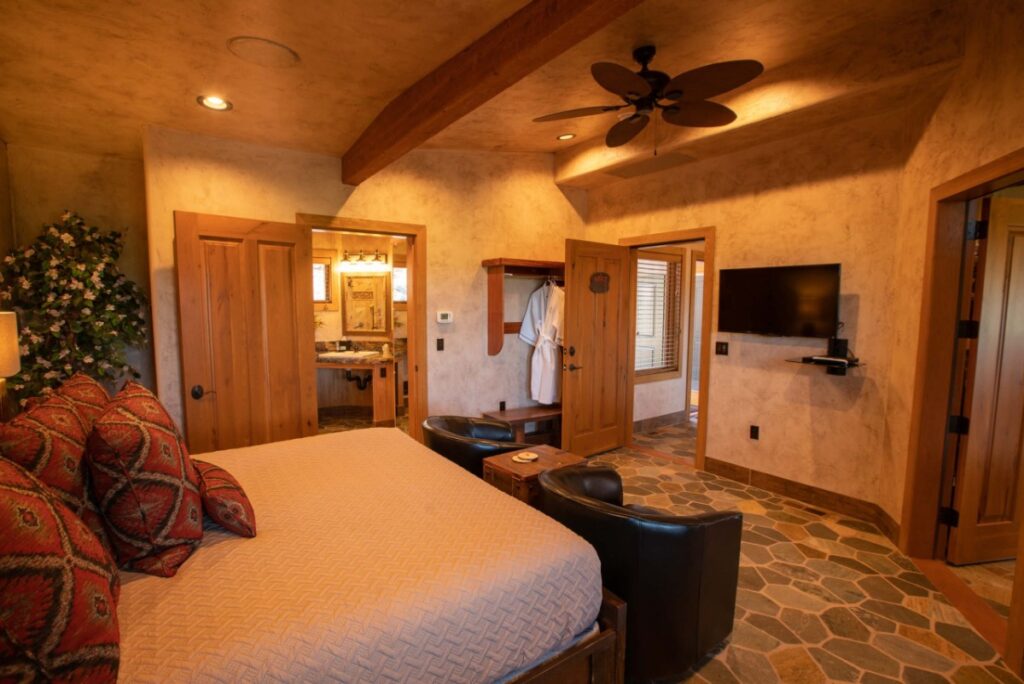 Inside a plush guest bedroom of a casita in Utah with bed and bathroom in wooden surroundings