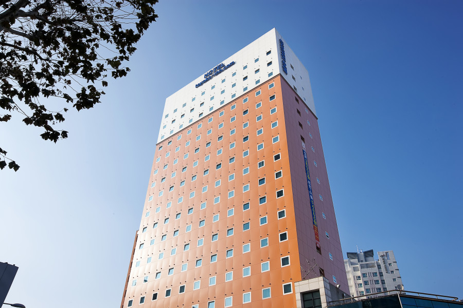 Exterior photo of a tall building painted orange backed by a blue sky