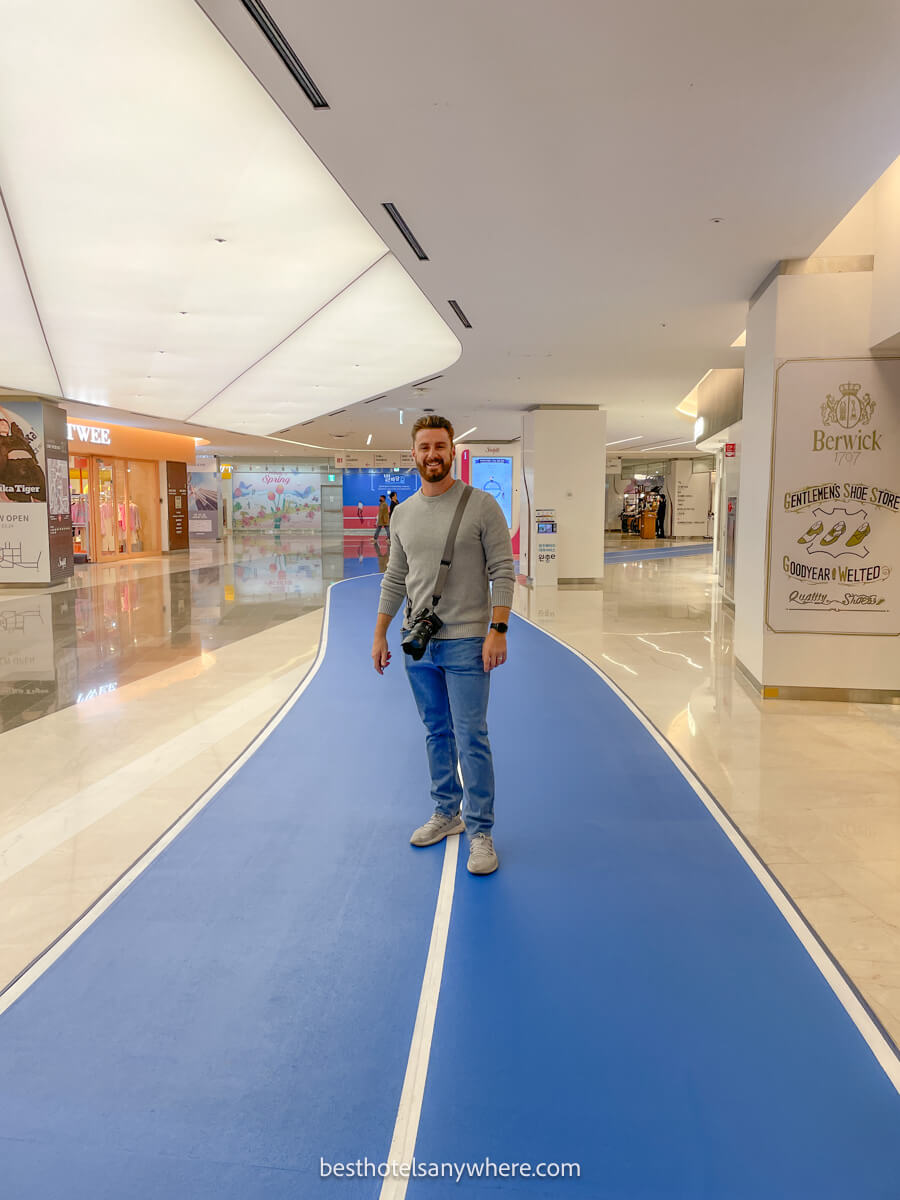 Tourist with a camera walking along a blue running track inside a shopping mall in Seoul