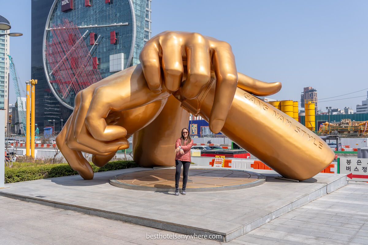 Tourist doing the Gangnam style wrist cross in front of the scultpure