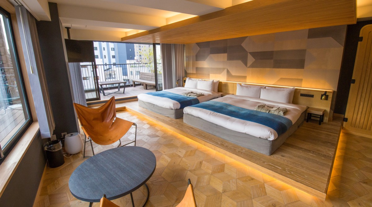Inside a guest bedroom at a hotel in Tokyo with two beds on a wooden floor and large windows