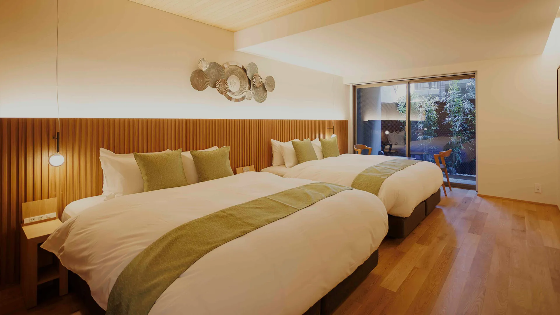 Inside a guest bedroom with two large beds and wooden floor leading to window