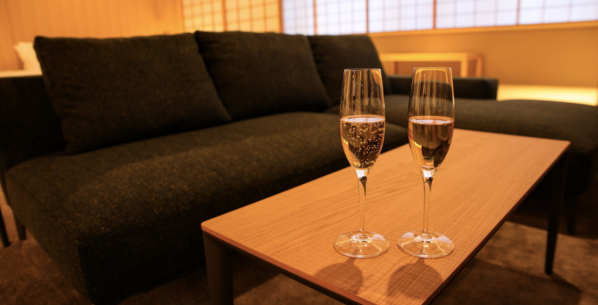 Table with two champagne glasses and a sofa with bed just visible in background