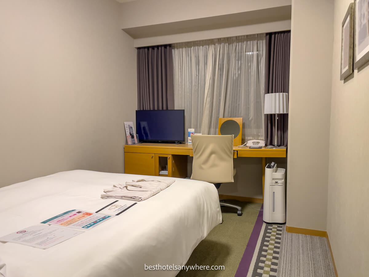 Inside a small guest bedroom at the Hotel Sunroute Plaza in Shinjuku Tokyo with bed and small desk