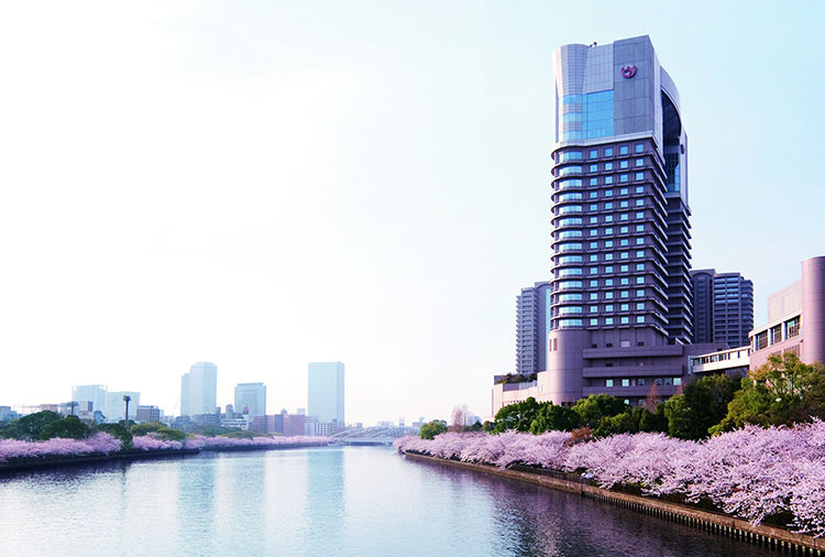 Exterior photo of Imperial Hotel Osaka along the riverbank with cherry blossom trees