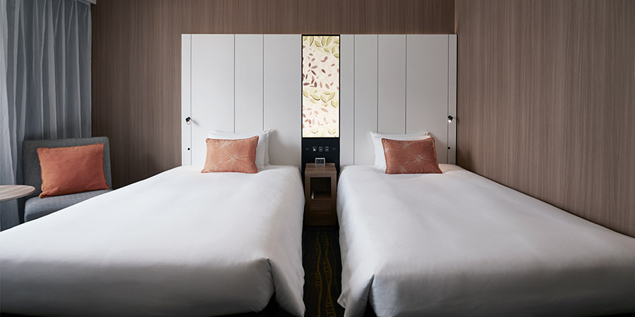 Two twin beds with white sheets in a Shibuya hotel room