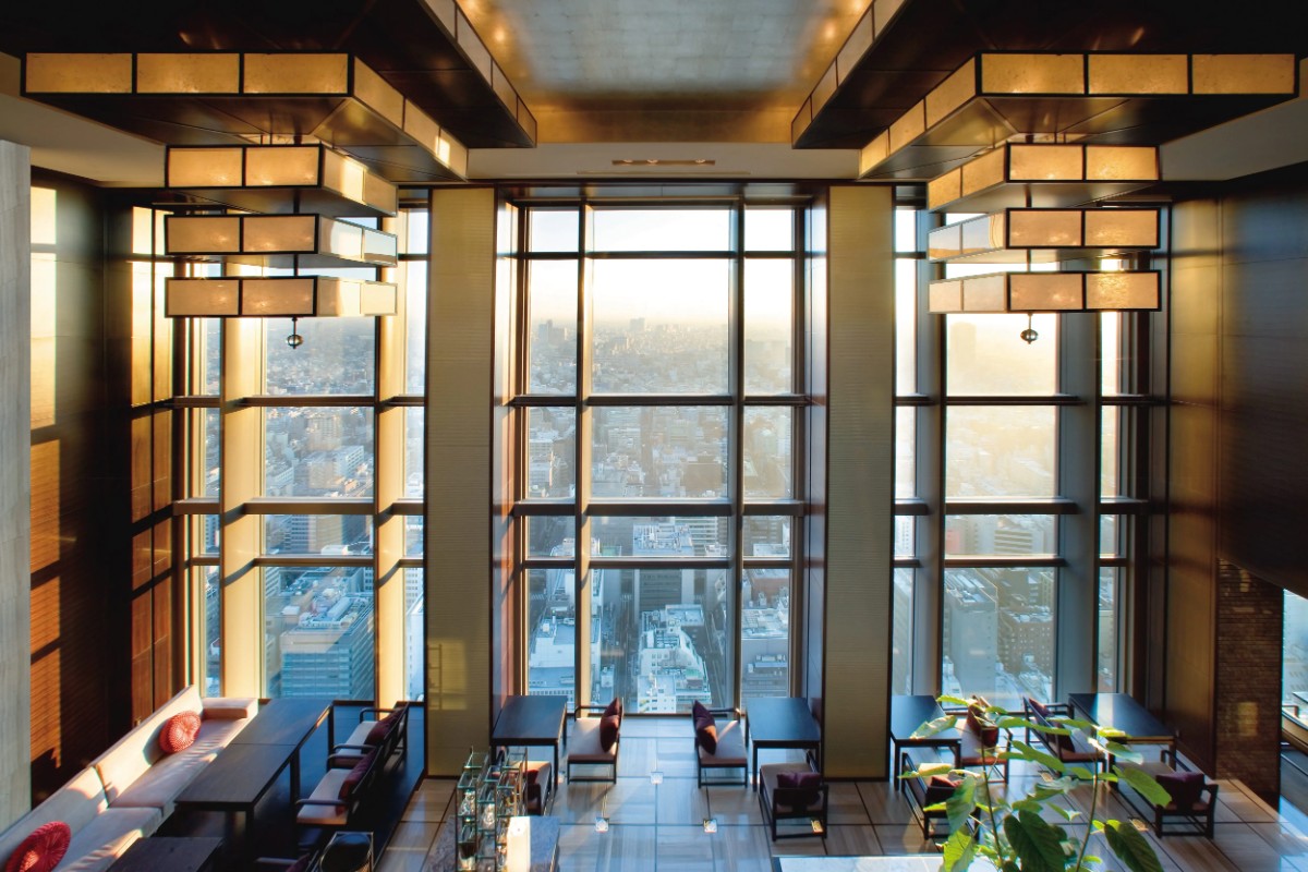 Photo of a luxury hotel lobby with tall glass windows and city views