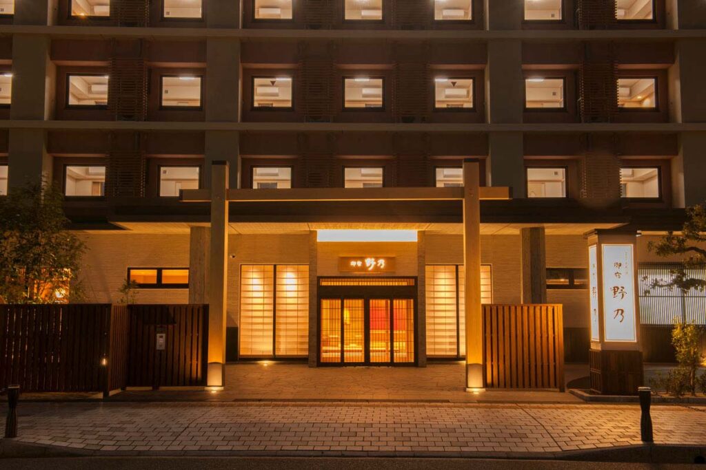 Exterior photo of the entrance to an onsen hotel in Osaka at night with lights