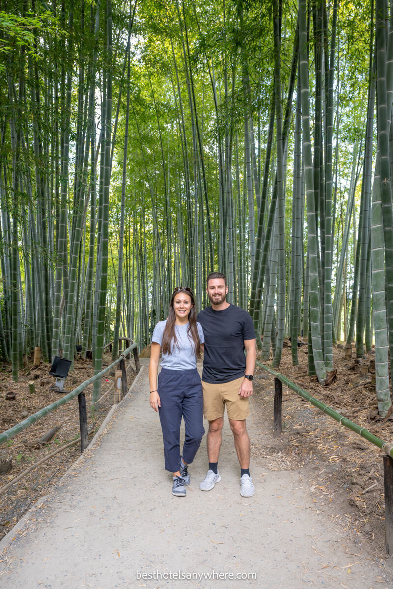 Couple standing together in the middle of a path surrounded by tall narrow bamboo trees