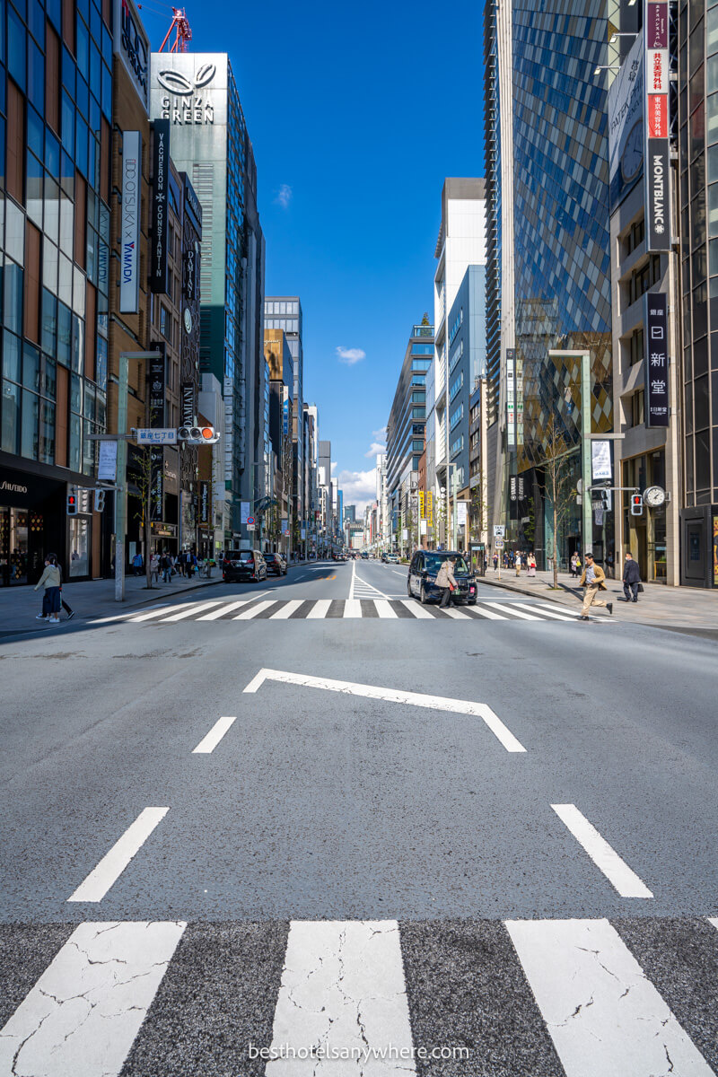 Photo of Ginza shopping street in Tokyo tall buildings flanking an empty road with blue sky