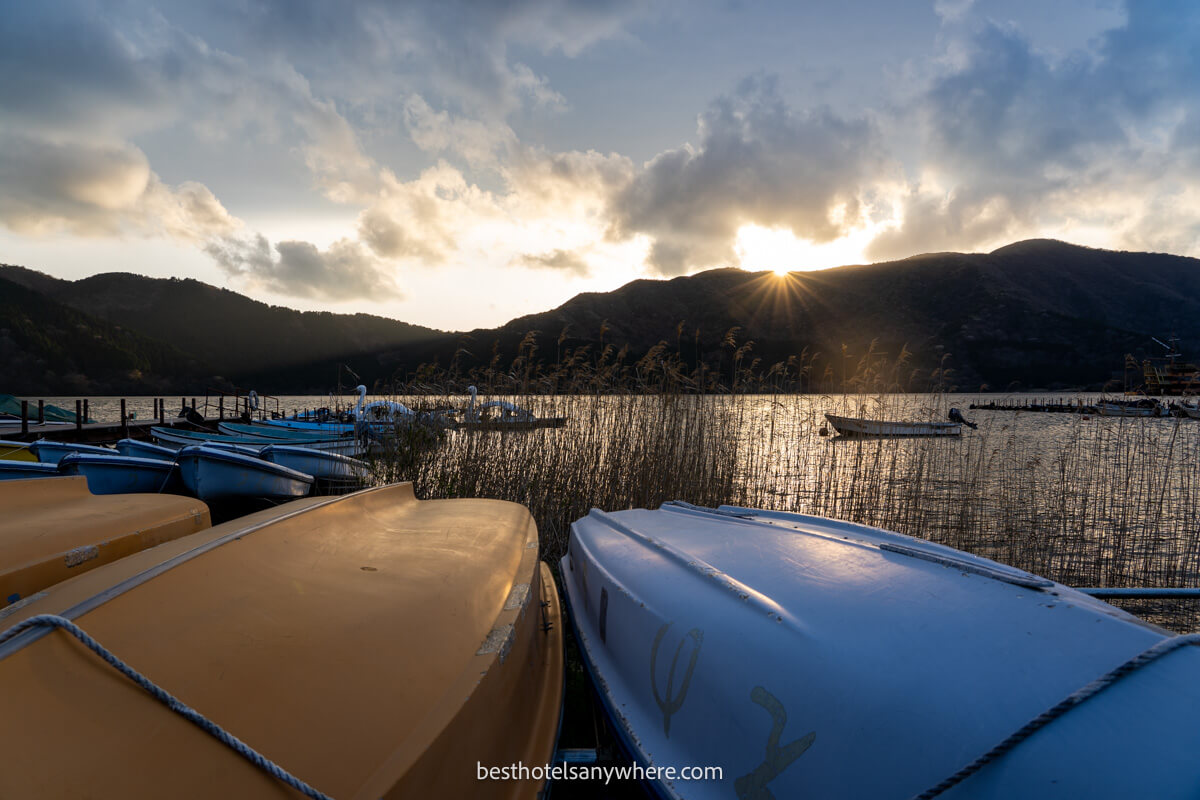 Canoes turned upside down on reedy shoreline with sunset over a lake