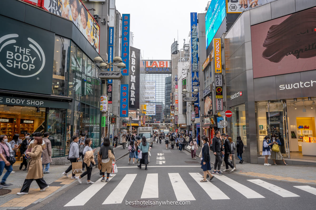 Shopping street in Shibuya with pedestrians walking over a zebra crossing 