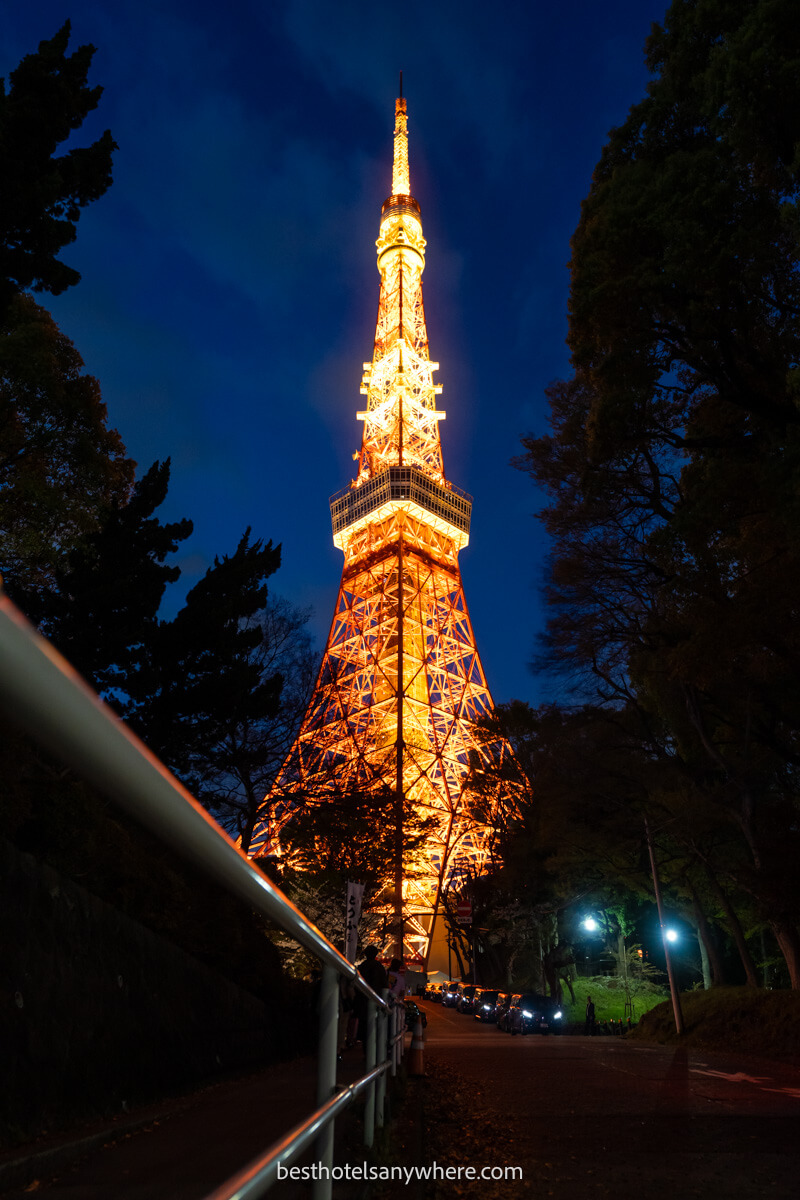 Tokyo Tower lit up orange at night from a road below