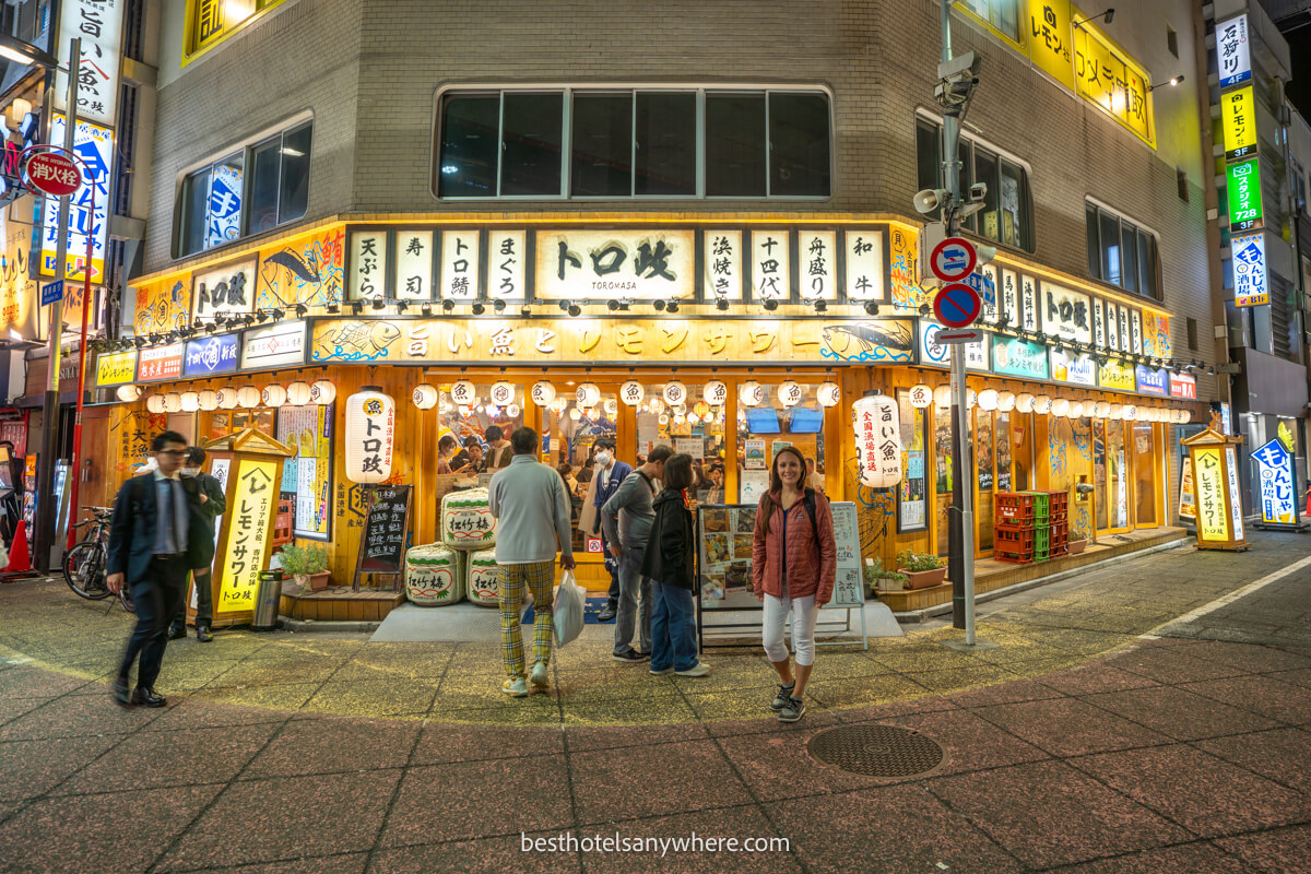Tourist stood outside a neon lit restaurant in Shinjuku at night