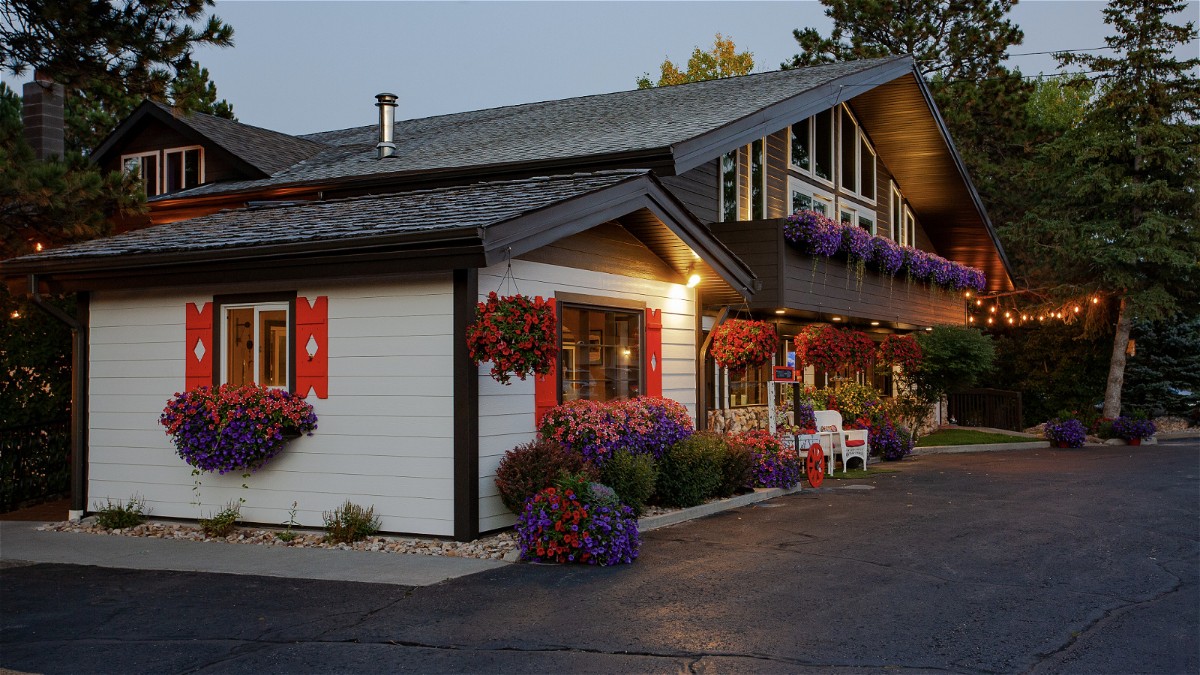 Exterior photo of the Bavarian Inn hotel in Custer South Dakota at dusk with lights at the entrance