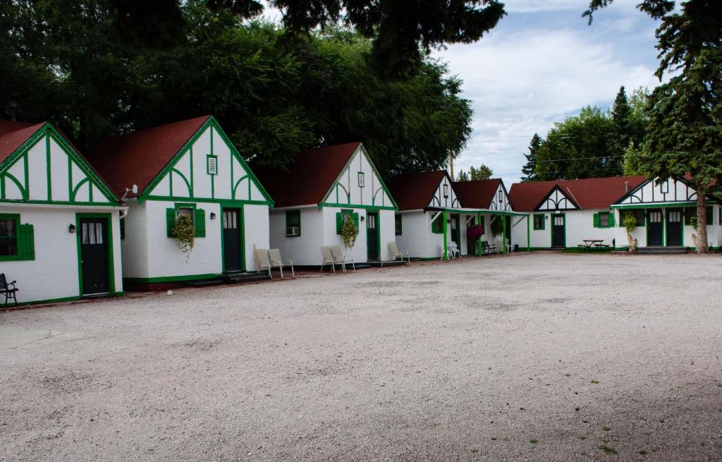 Exterior photo of detached cabins painted white in a row with trees behind