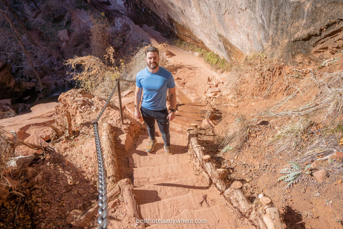 Hiker in blue t shirt walking up stairs in a dusty red landscape