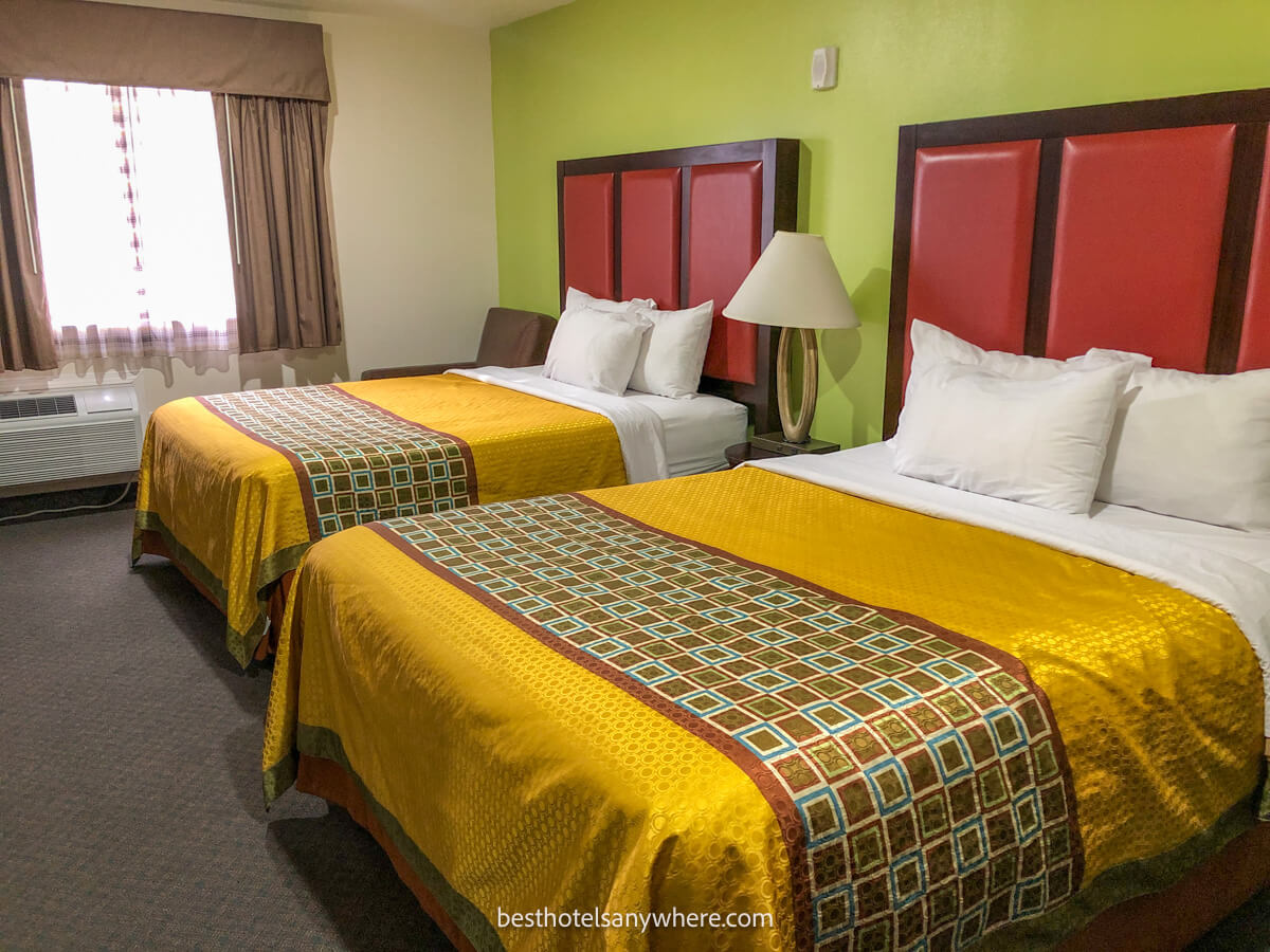 Inside a guest bedroom at a hotel in La Verkin Utah featuring two beds with gold covers