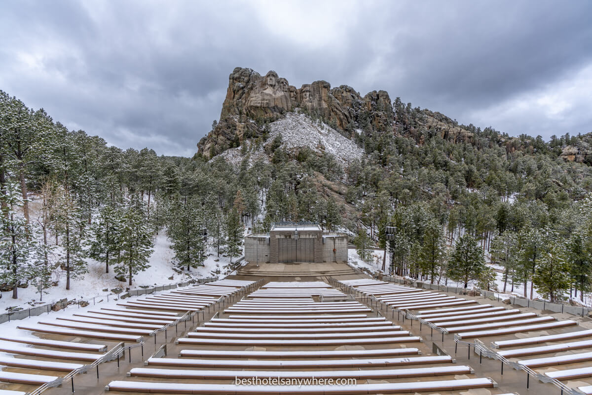 View of Mt Rushmore from t he Lincoln Borglum Amphitheater on a cloudy day with snow on the ground