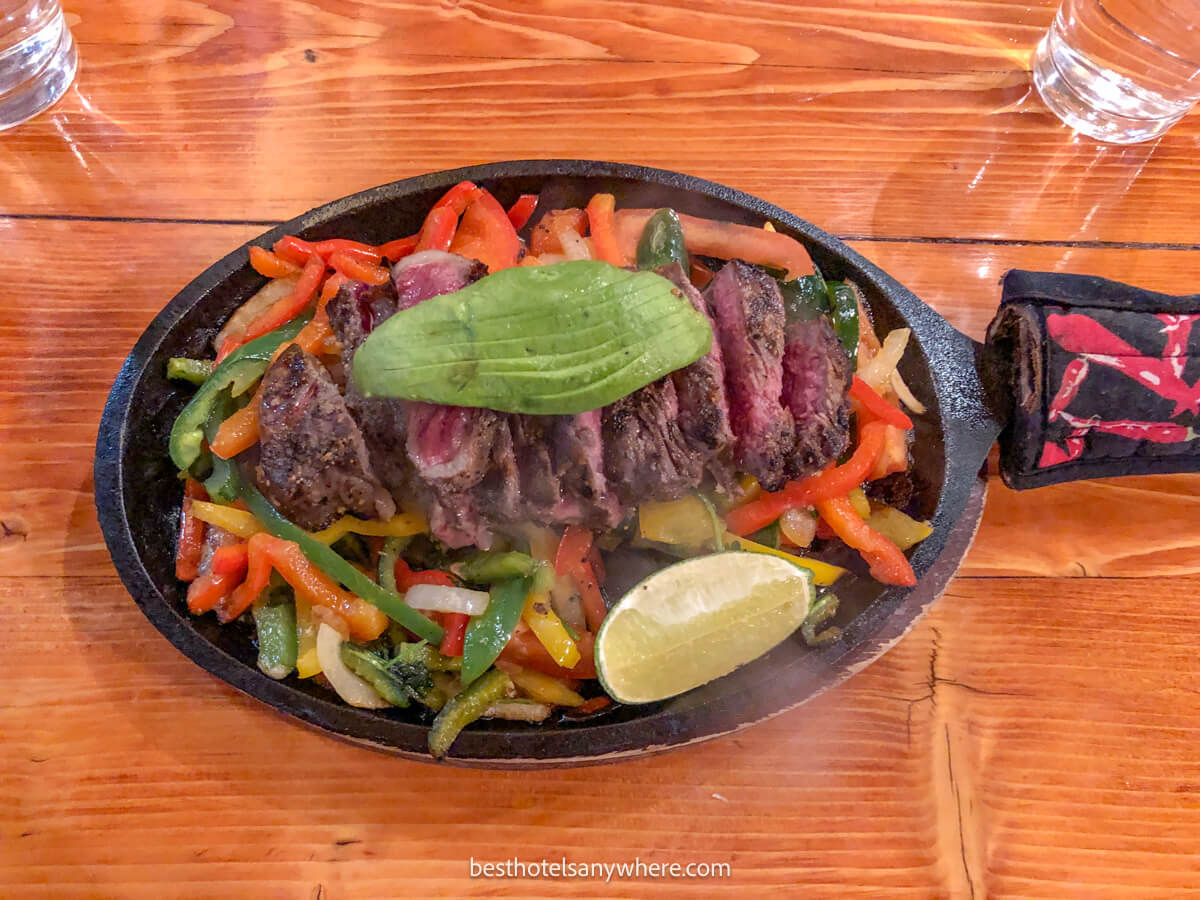 Hot plate filled with peppers, steak and lime on a table