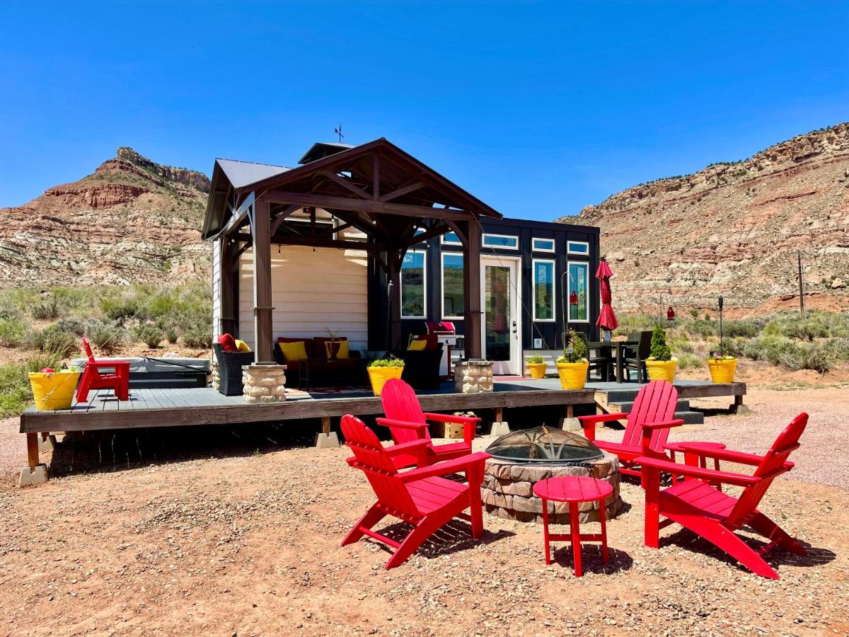 Fire pits with chairs and a tiny house on a deck with deep blue sky and red rock hills