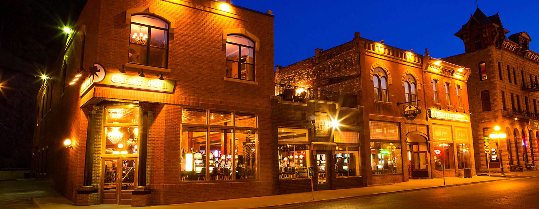 Exterior photo of a hotel in Deadwood SD at night with lights illuminating the building