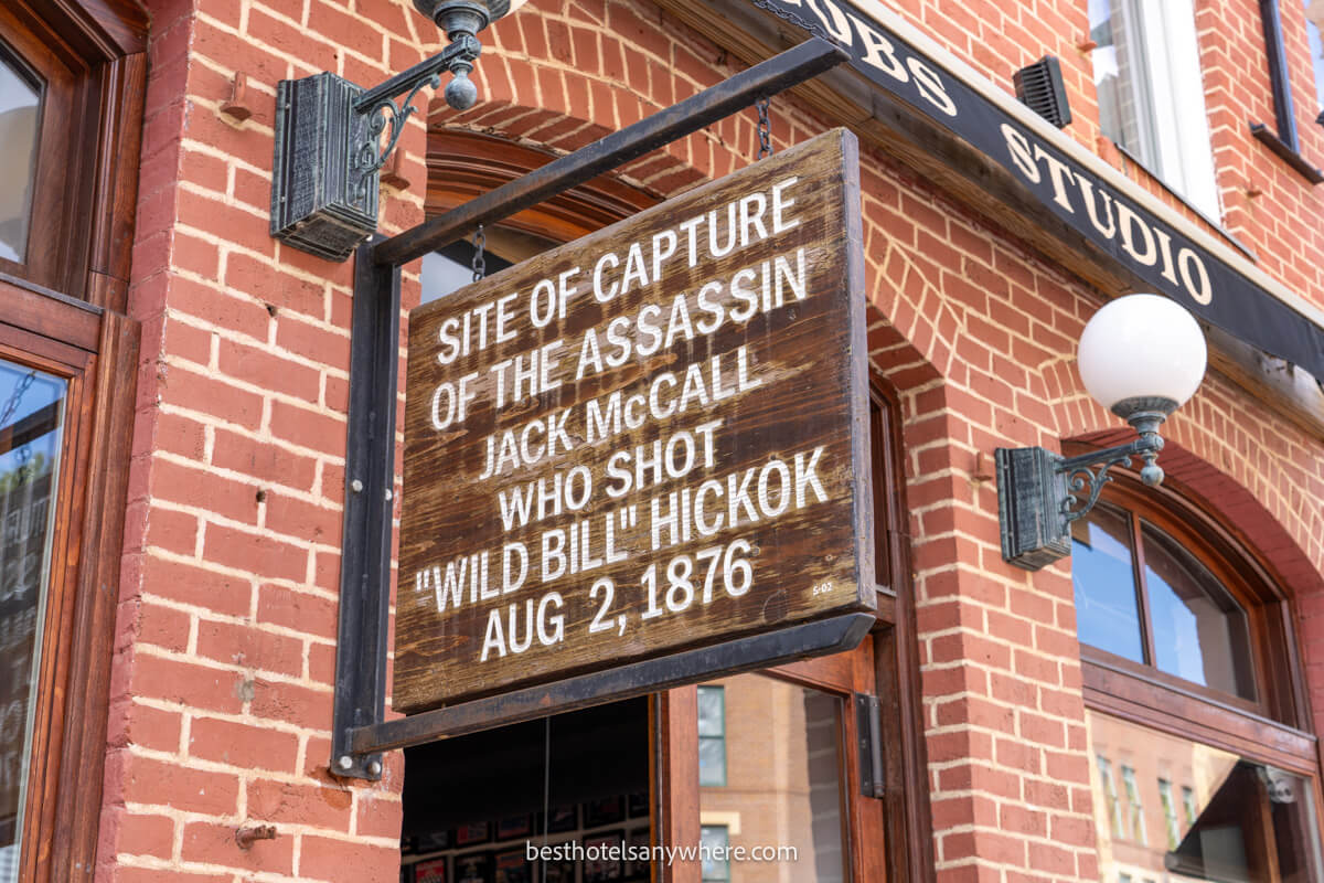 Wooden sign hanging on a wall showing the site of where wild bill hickock died in 1876