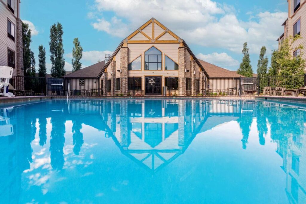 Swimming pool with reflection of building and trees at Bryce Canyon Grand Hotel on a sunny day with light clouds