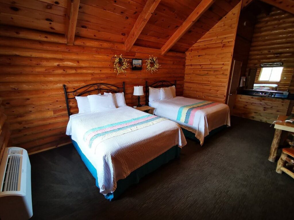Inside a log cabin with two queen beds and wooden furniture