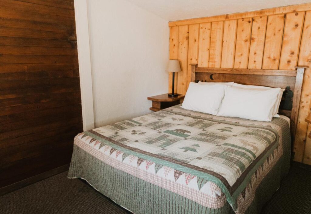 Queen sized bed with covers and a wooden backboard in a guest bedroom
