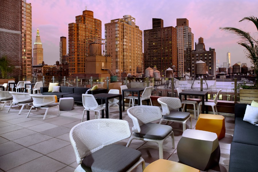 Rooftop terrace at night with buildings in background and pink sky