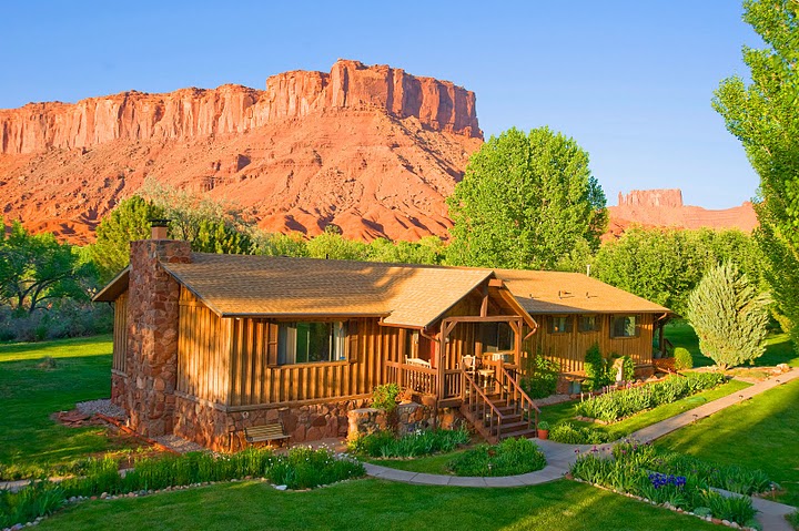 Wooden building surrounded by lush green grass and backed by red rocks in Utah