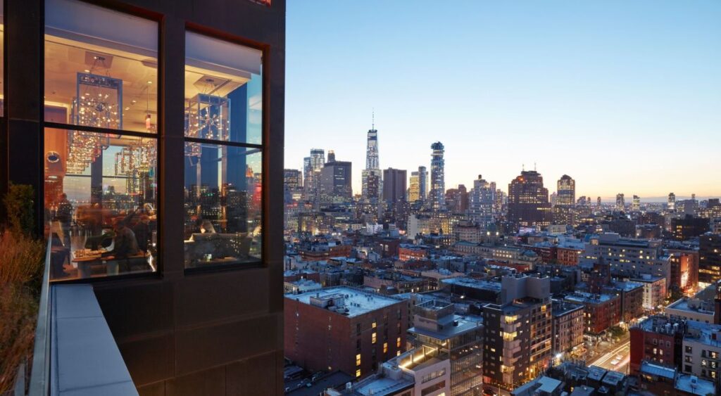 Rooftop terrace overlooking restaurant and midtown manhattan in the distance at twilight