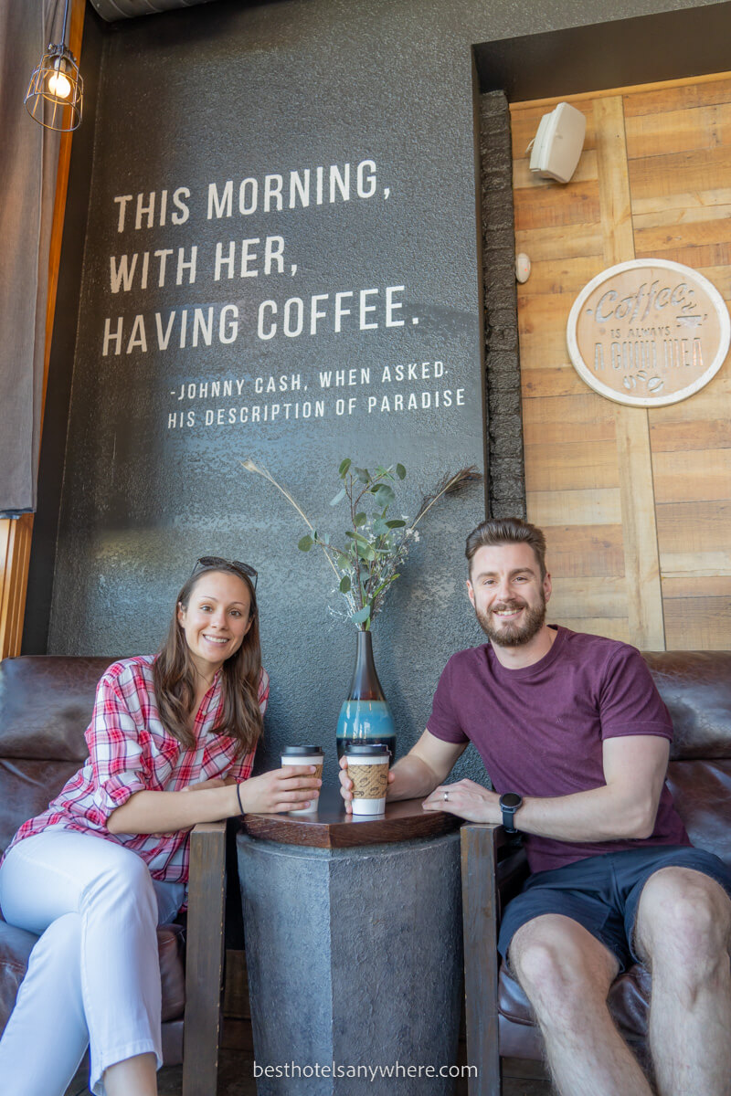 Couple enjoying a morning coffee in chairs under a sign with quote by Johnny Cash