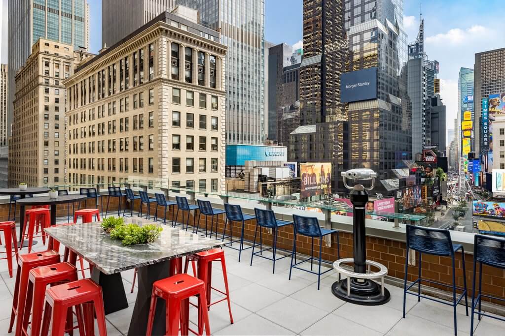 Outdoor terrace with chairs and tables looking over Times Square from M Social Hotel in NYC