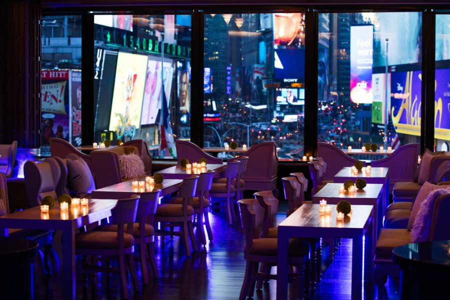 R Lounge overlooking Times Square at night with deep blue colors and dark shadows