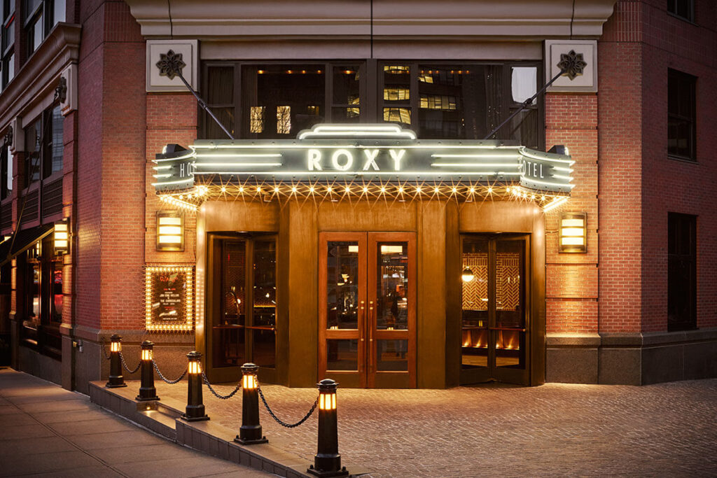 Exterior photo of Roxy Hotel in SoHo NYC lit up at night on a street corner