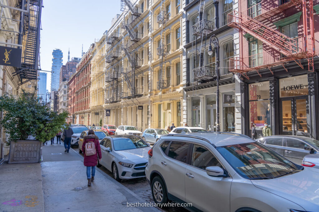Person walking down a cobblestone street with colorful buildings in SoHo NYC